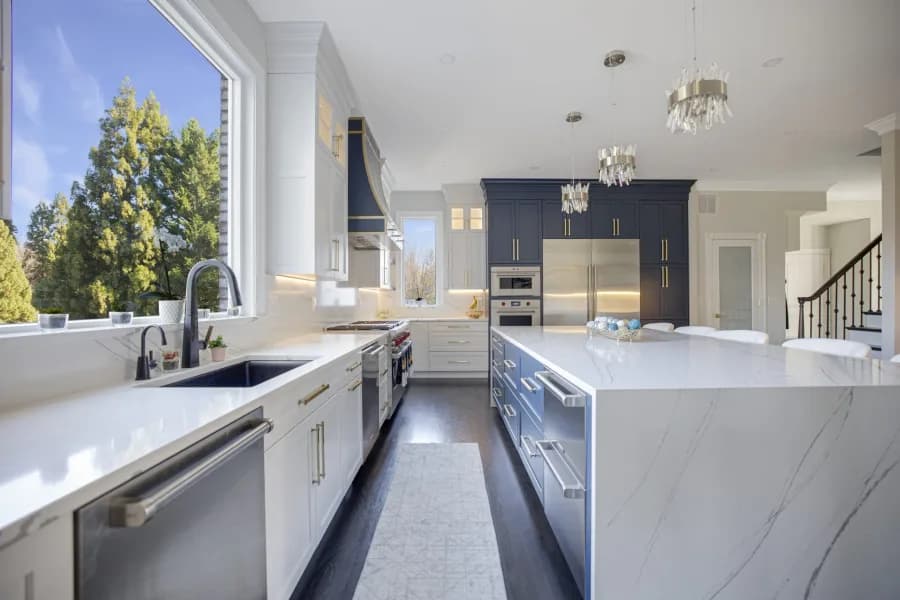 Fully custom navy and white kitchen with quartz countertops and a large window
