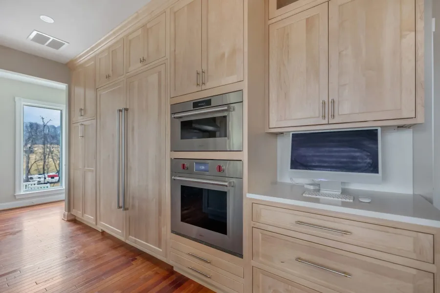 Clean-lined kitchen with light natural wood cabinetry and built-in ovens