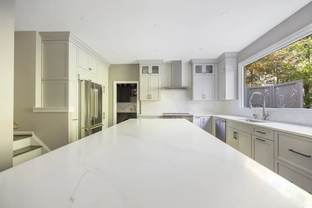 Kitchen with white shaker cabinets, marble countertops and a spacious island