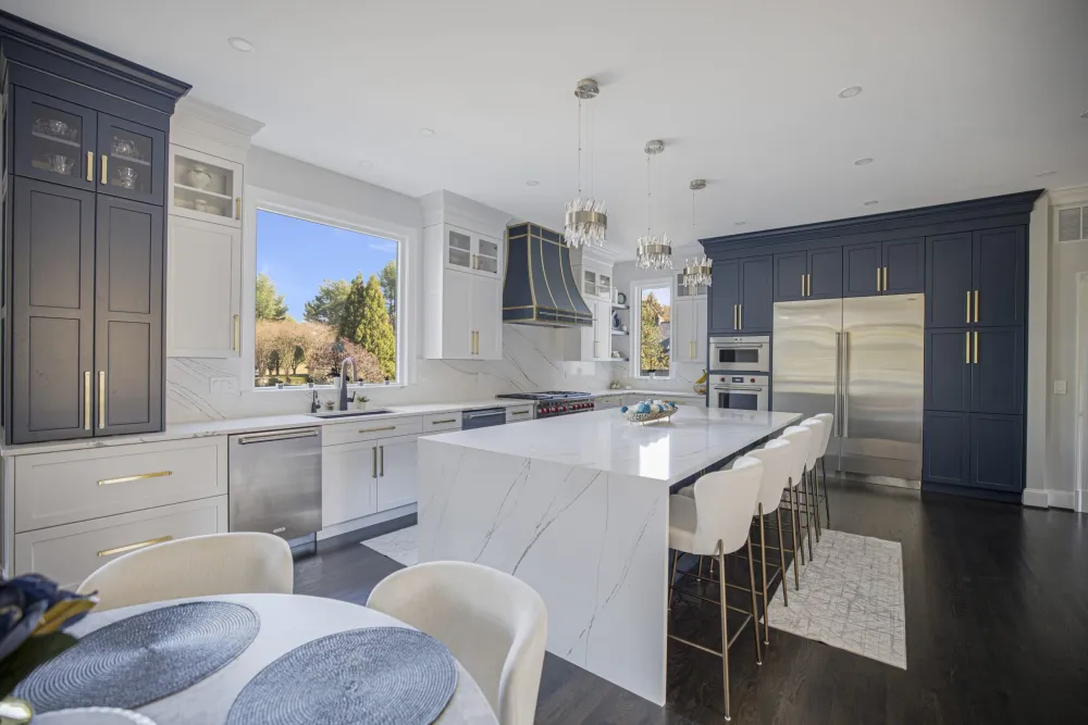 Custom kitchen with a quartz waterfall island, white cabinetry and pendant lighting